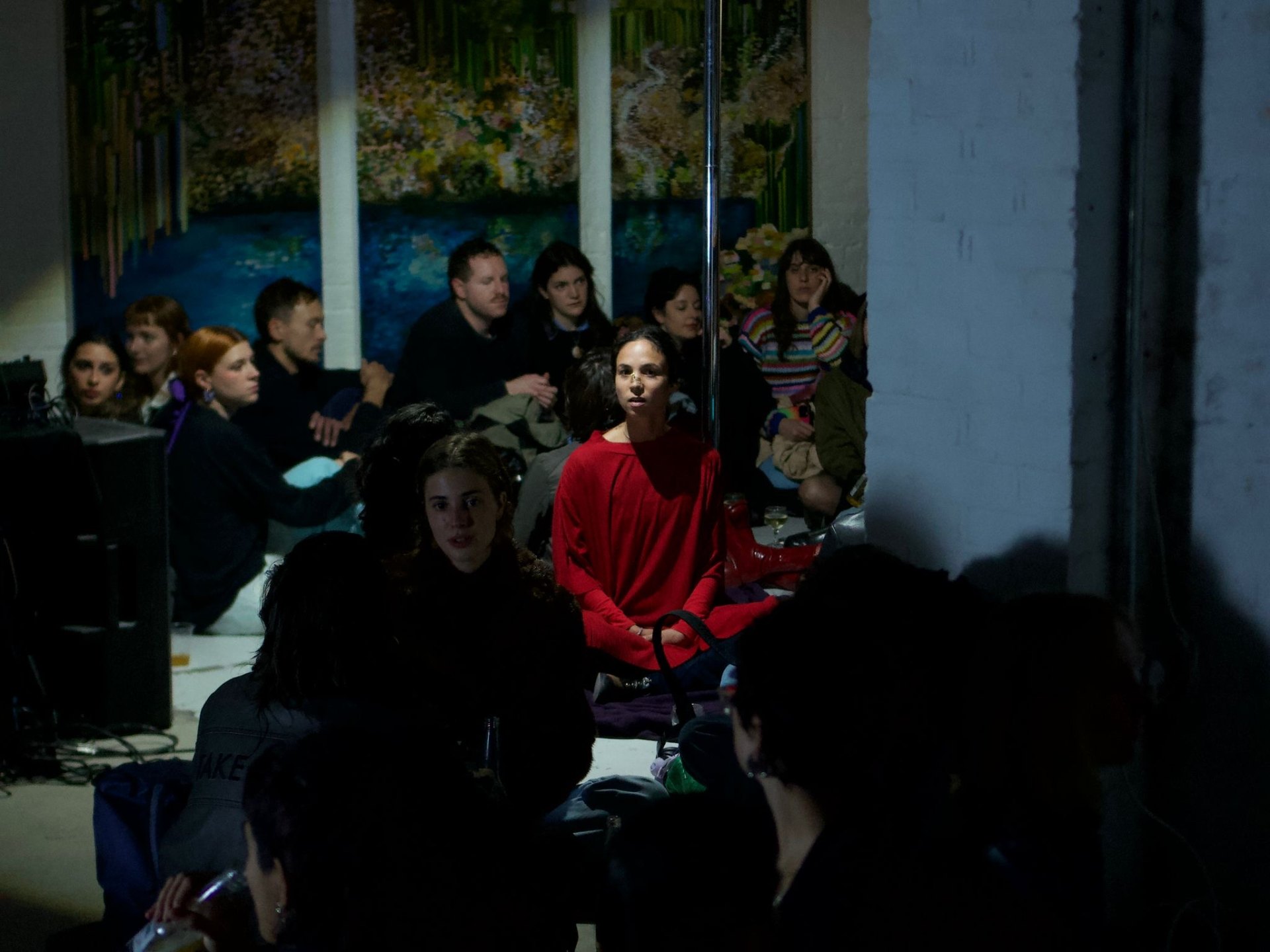 Time To Kiss A Stranger — a participant in a red sweater seated among an audience in a dimly lit participatory performance